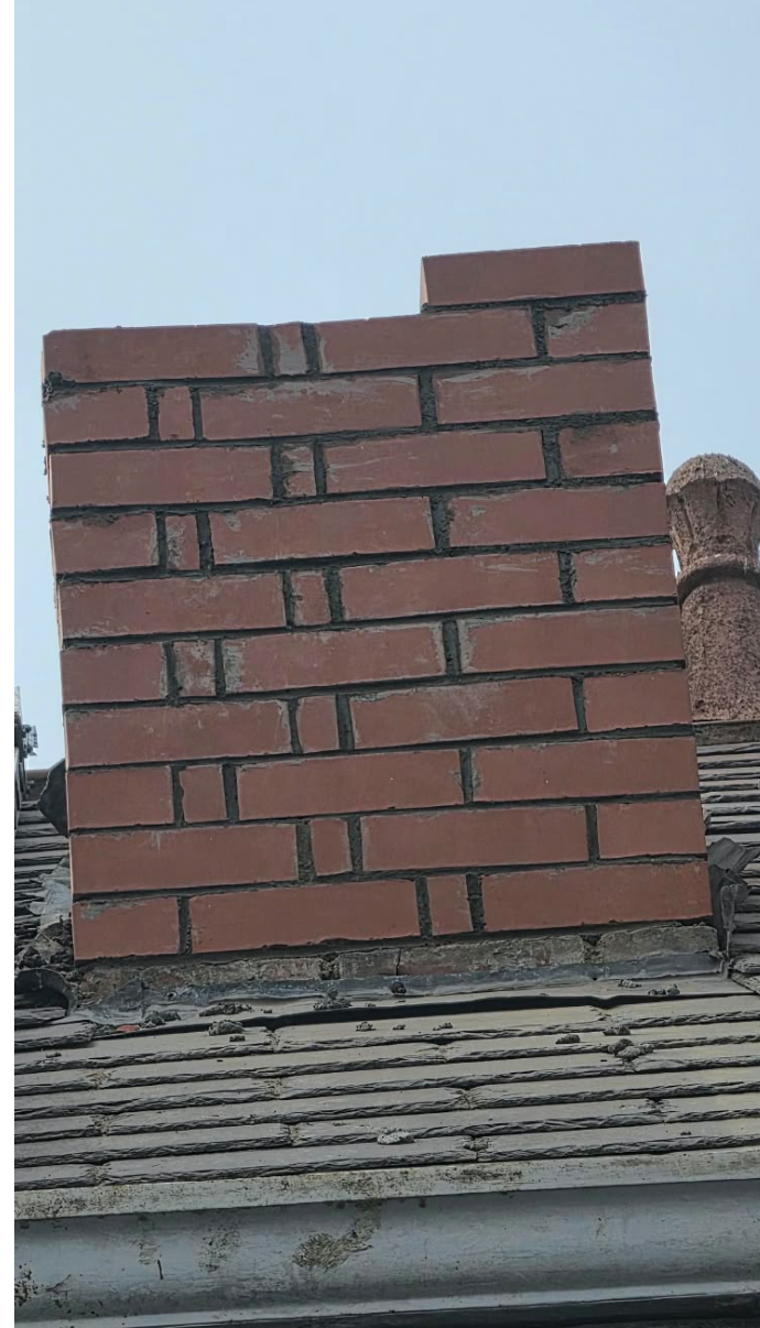 Freshly rebuilt brick chimney above a slate roof