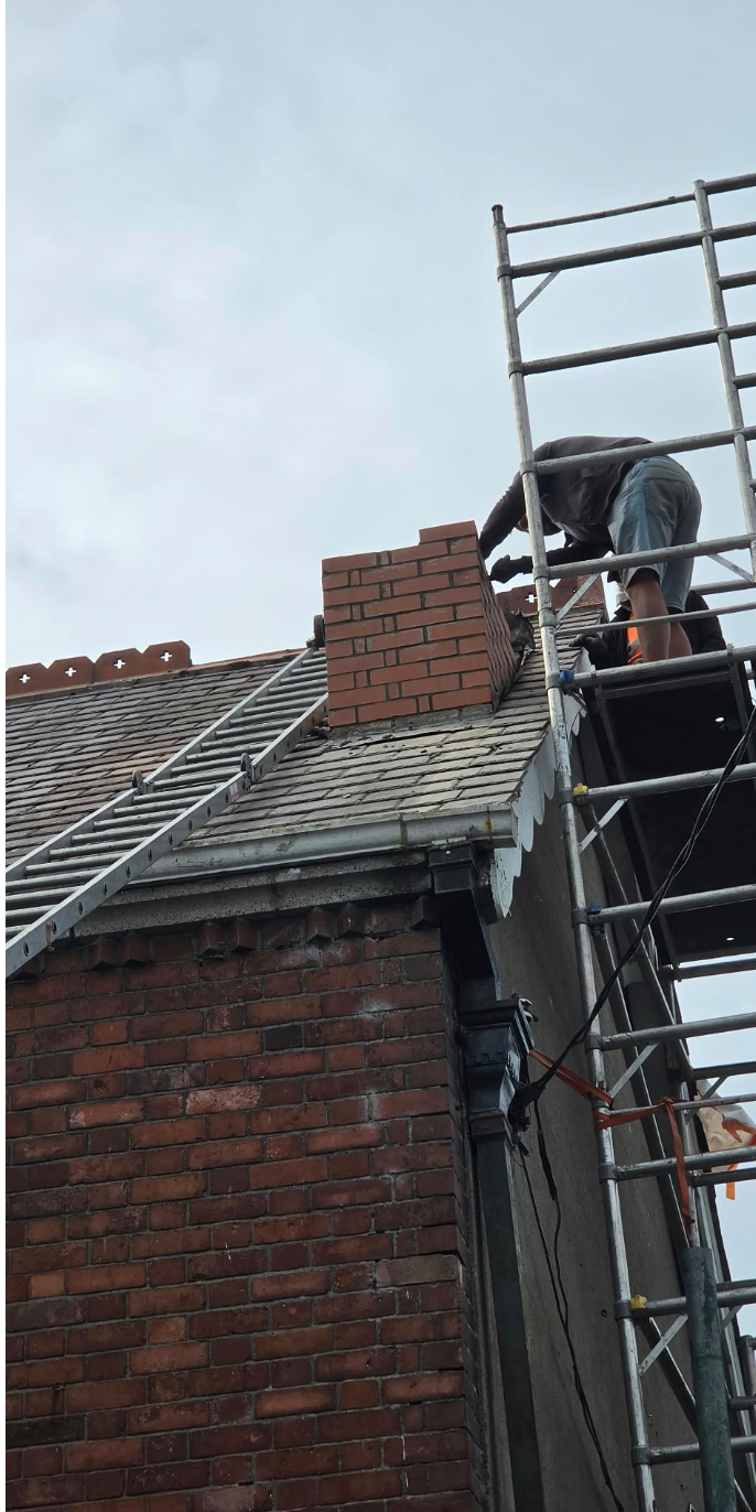 Roofer working beside a brick chimney from scaffolding